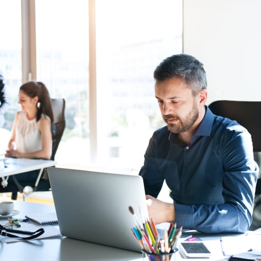 Three people work on computers in a bright modern office.