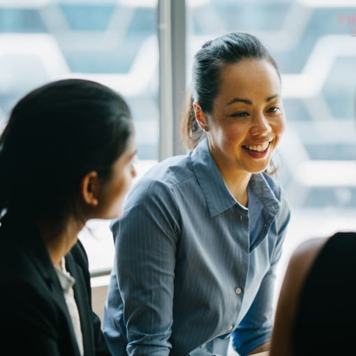 Three young professionals talk together in front of a frosted glass window.