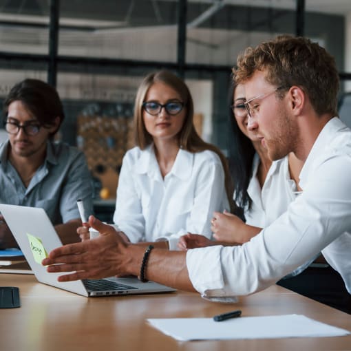 Young professionals sit at a conference table.