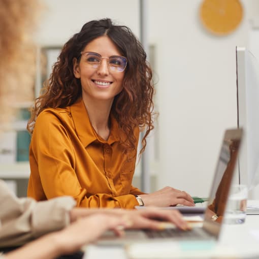 Seated person interacts with a colleague in an office setting.