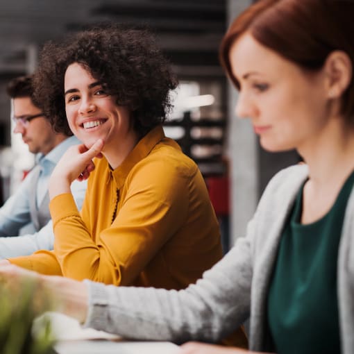 Employee in office smiling while working with coworkers