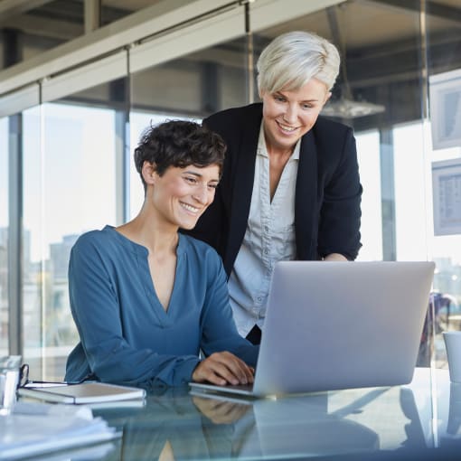 Two women looking at laptop together in office