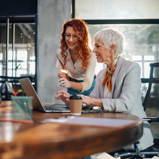 Two generation workers collaborating on a project on a laptop