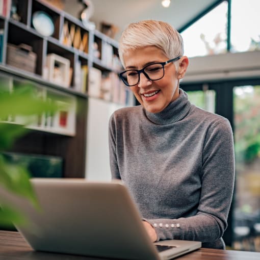 An HR professional digitally manages their workload on a laptop in their home office.