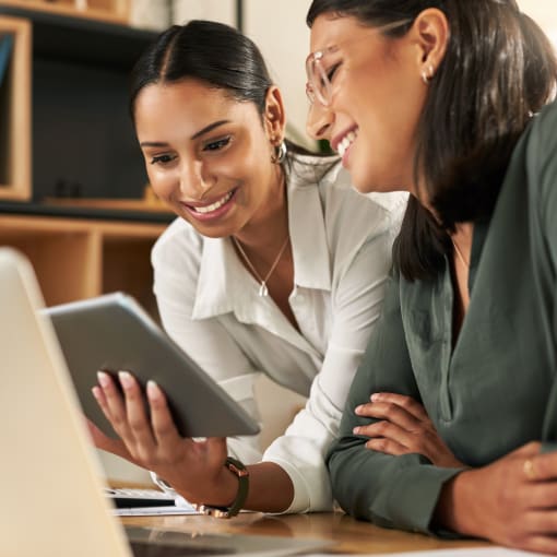 Two businesswomen using a digital tablet to oversee work