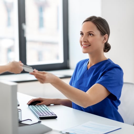 A patient handing in their insurance card at a hospital registration counter.