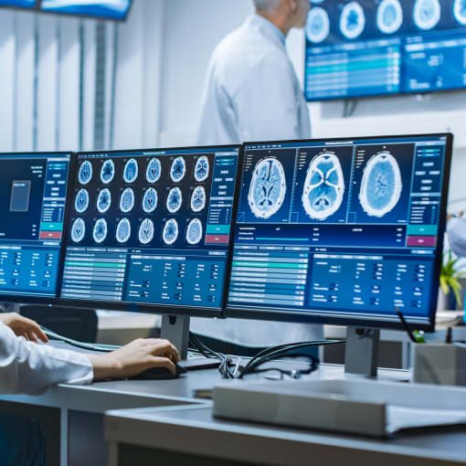 Woman neuroscientist surrounded by monitors showing brain scans