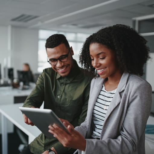 A woman holding a tablet in a discussion with a man.