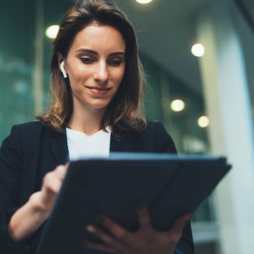A woman with short hair smiling and holding a tablet.