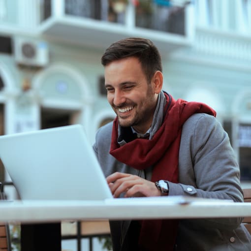 A webinar attendee smiles at their laptop, pleased with their new knowledge and insight.