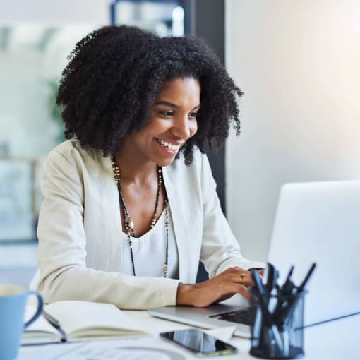 Person smiles while working at a white laptop.