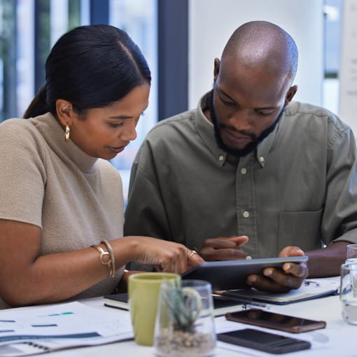 Two office coworkers looking at a tablet