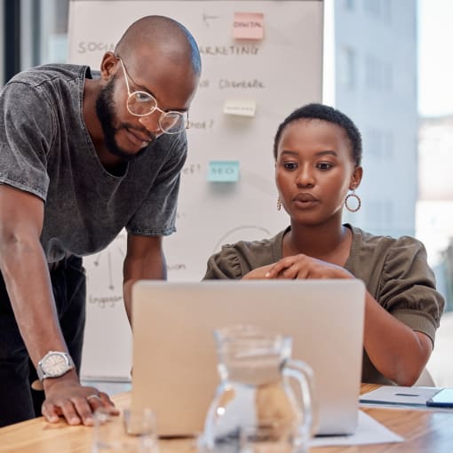 Two office coworkers looking at a laptop