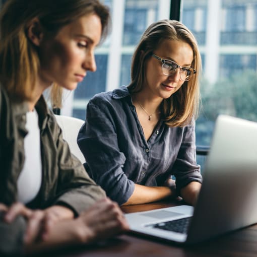 Two female colleagues looking at a laptop