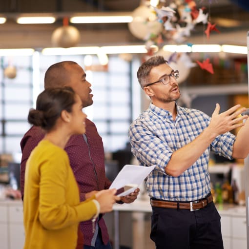 Three office coworkers looking at a whiteboard