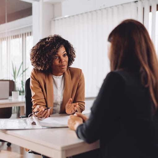 Two female colleagues talking at a desk