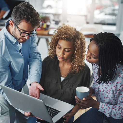 Three technology professionals looking at a laptop