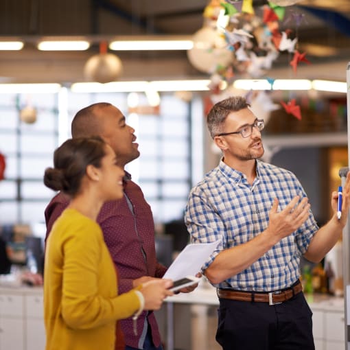 Three coworkers looking at a whiteboard