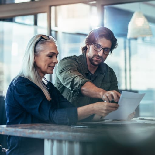 man and woman in office look at a laptop