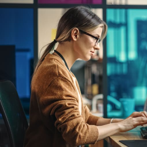 An IT employee works at a desktop station with three monitors.