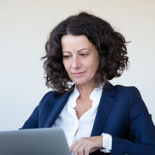 Businessperson sits at a chair with a laptop.