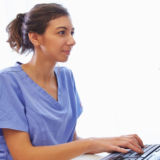 Person sits at a desktop computer with their hands on the keyboard.