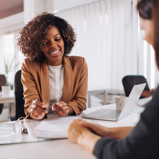 Two people discussing an insurance policy while sitting at a desk in a meeting room.