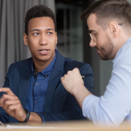 Two people sit in discussion, with one holding a tablet computer.