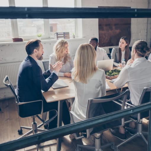 Group of people sit at a conference room in deep discussion.