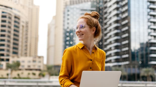 Young woman sitting outside and working on laptop