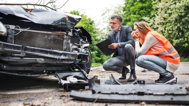 Man and woman examine damage to a car after an accident