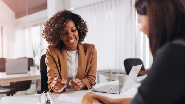 Two people discussing an insurance policy while sitting at a desk in a meeting room.