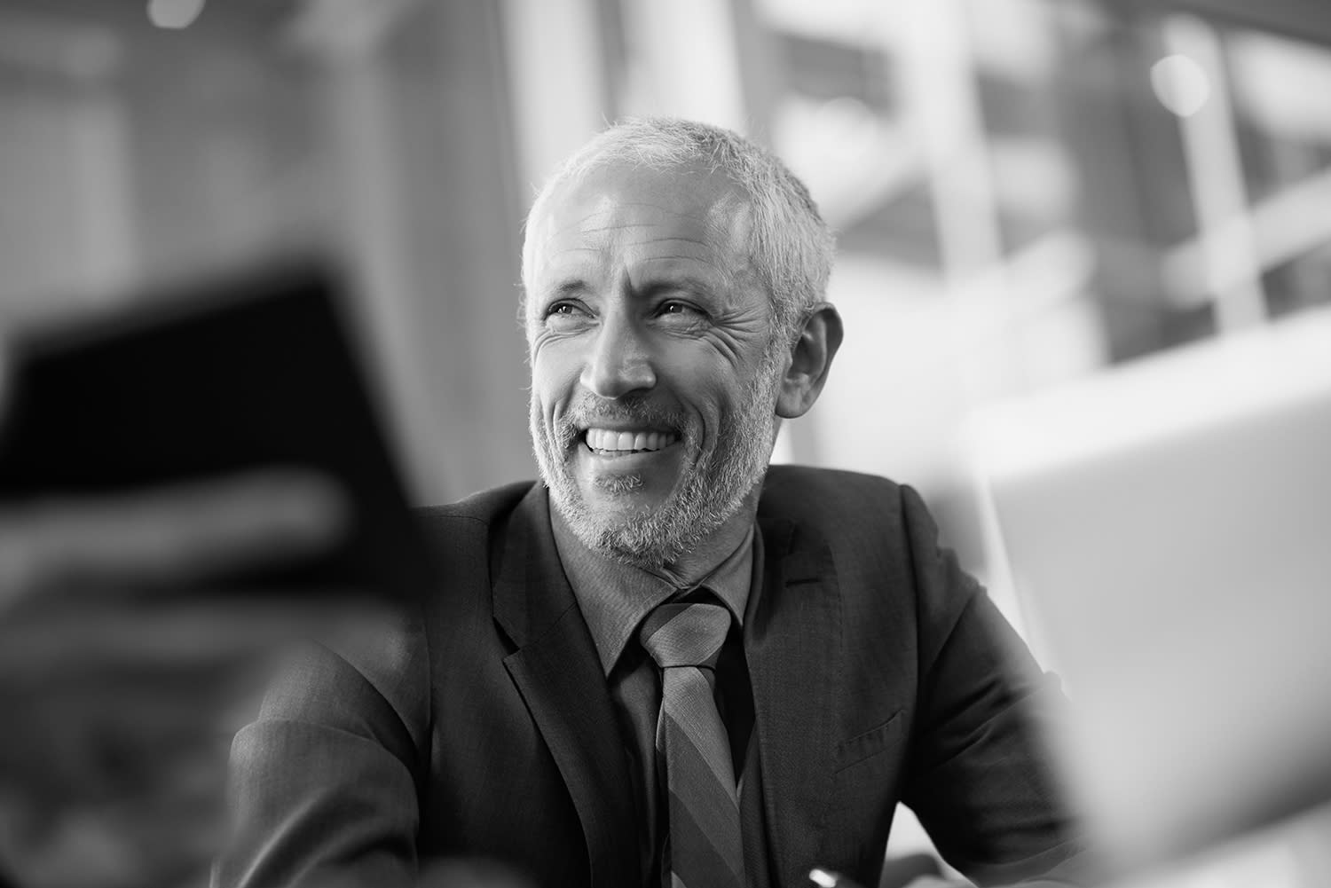 Black and white photo of a person in a dark suit, smiling.