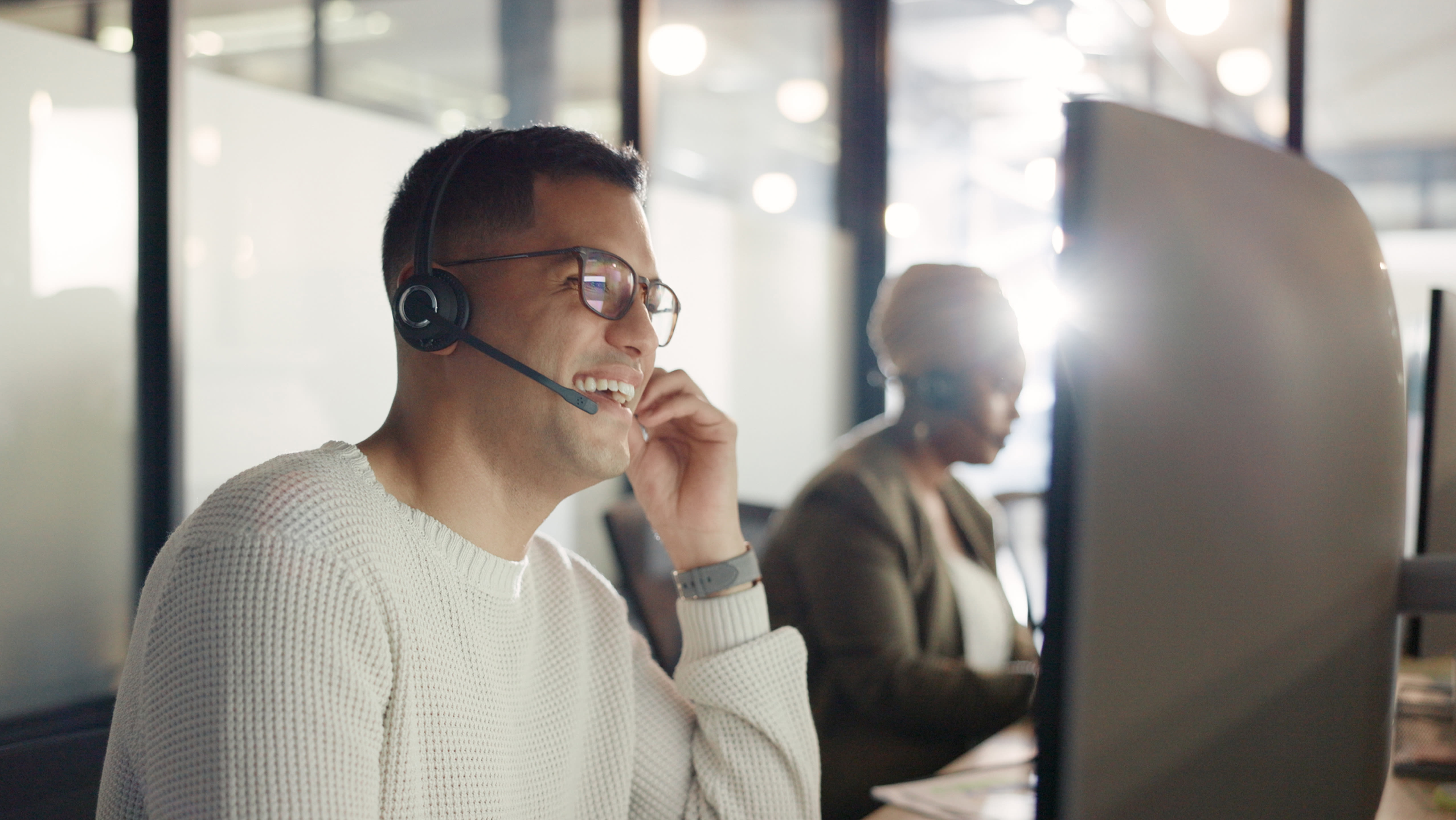 Man on a headphone works on a computer at a call center.