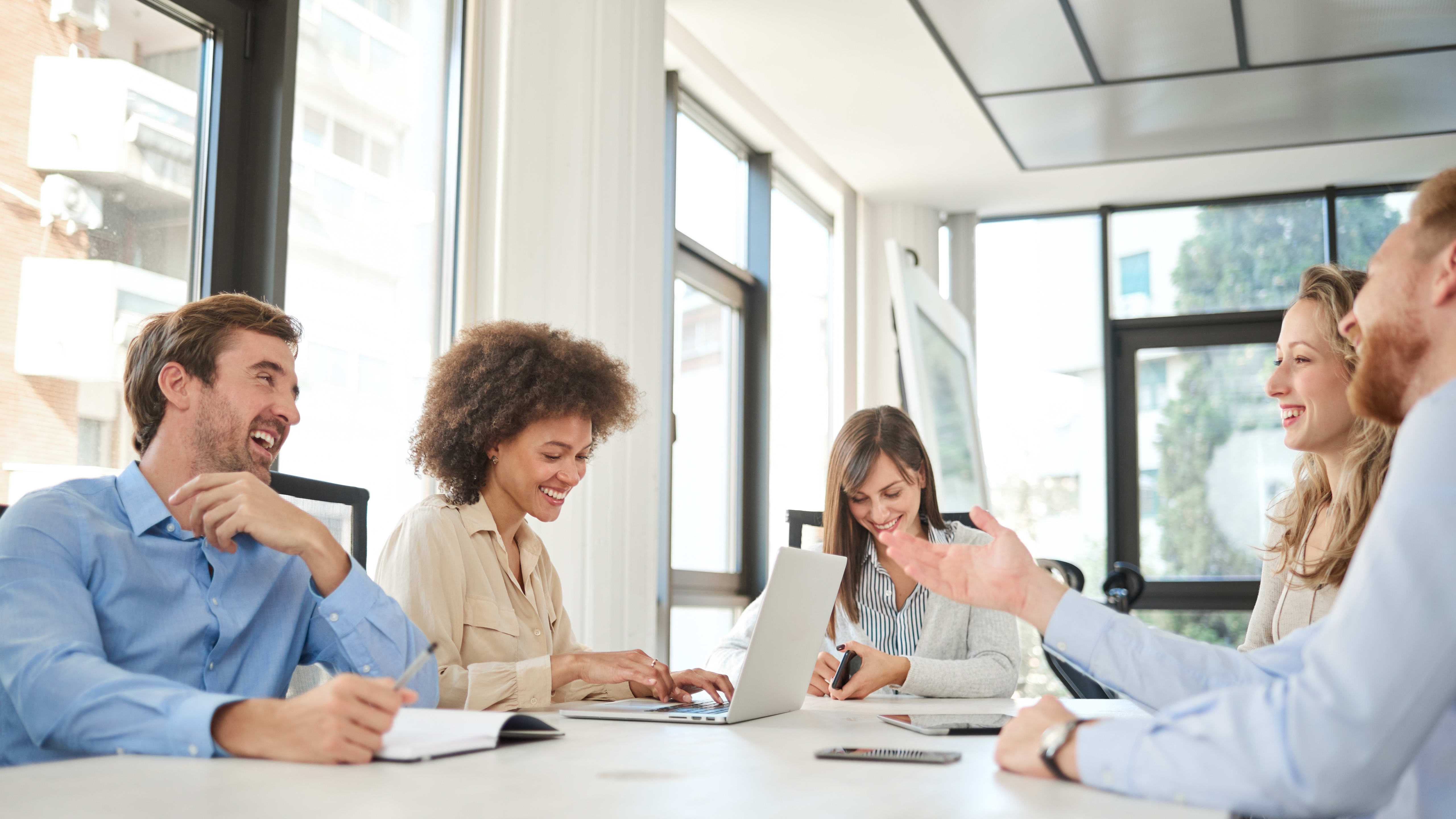 Five professionals sit in a bright conference room.