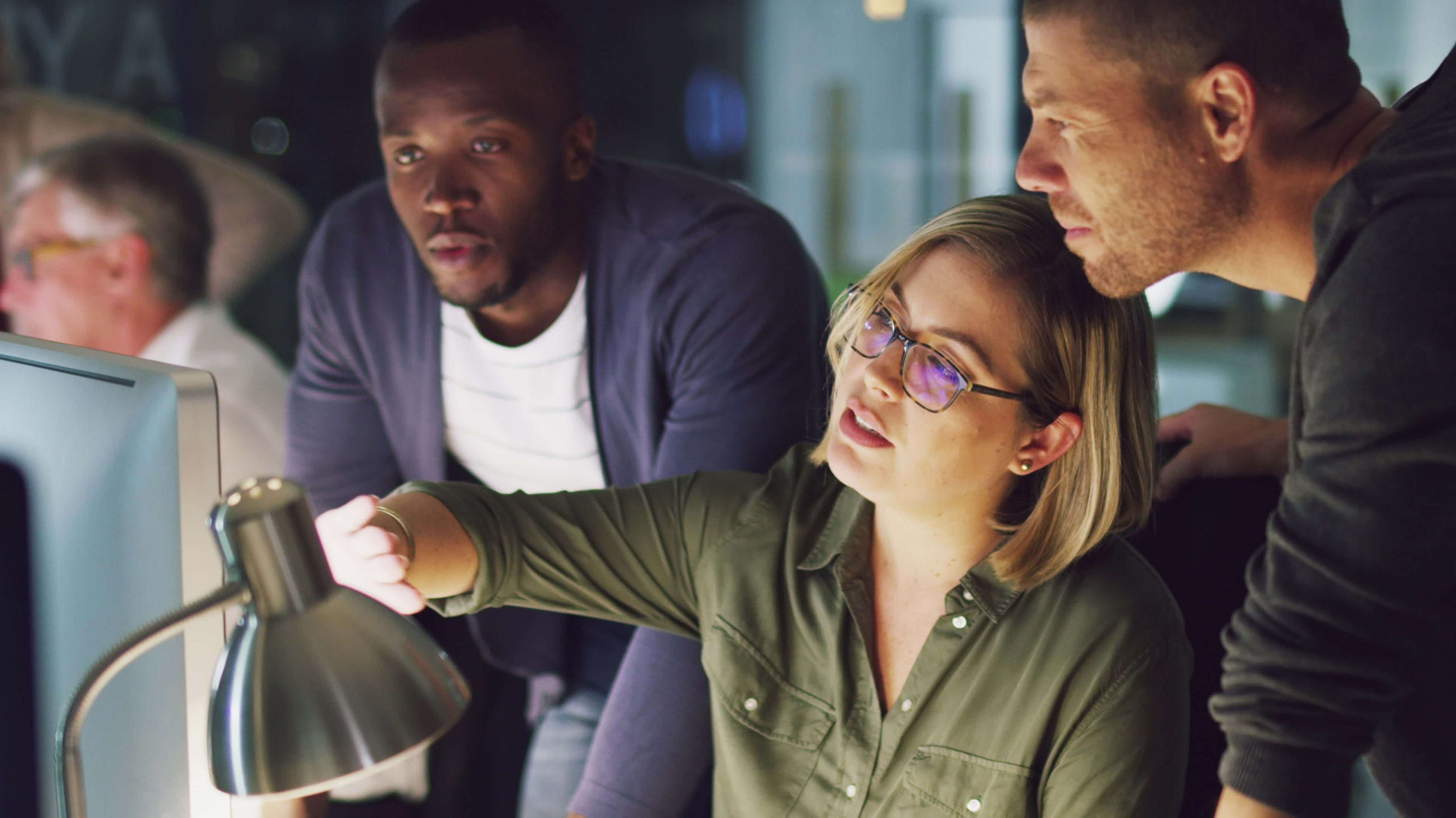 Group of employees collaborate in front of a computer, discussing a document stored in OnBase. 