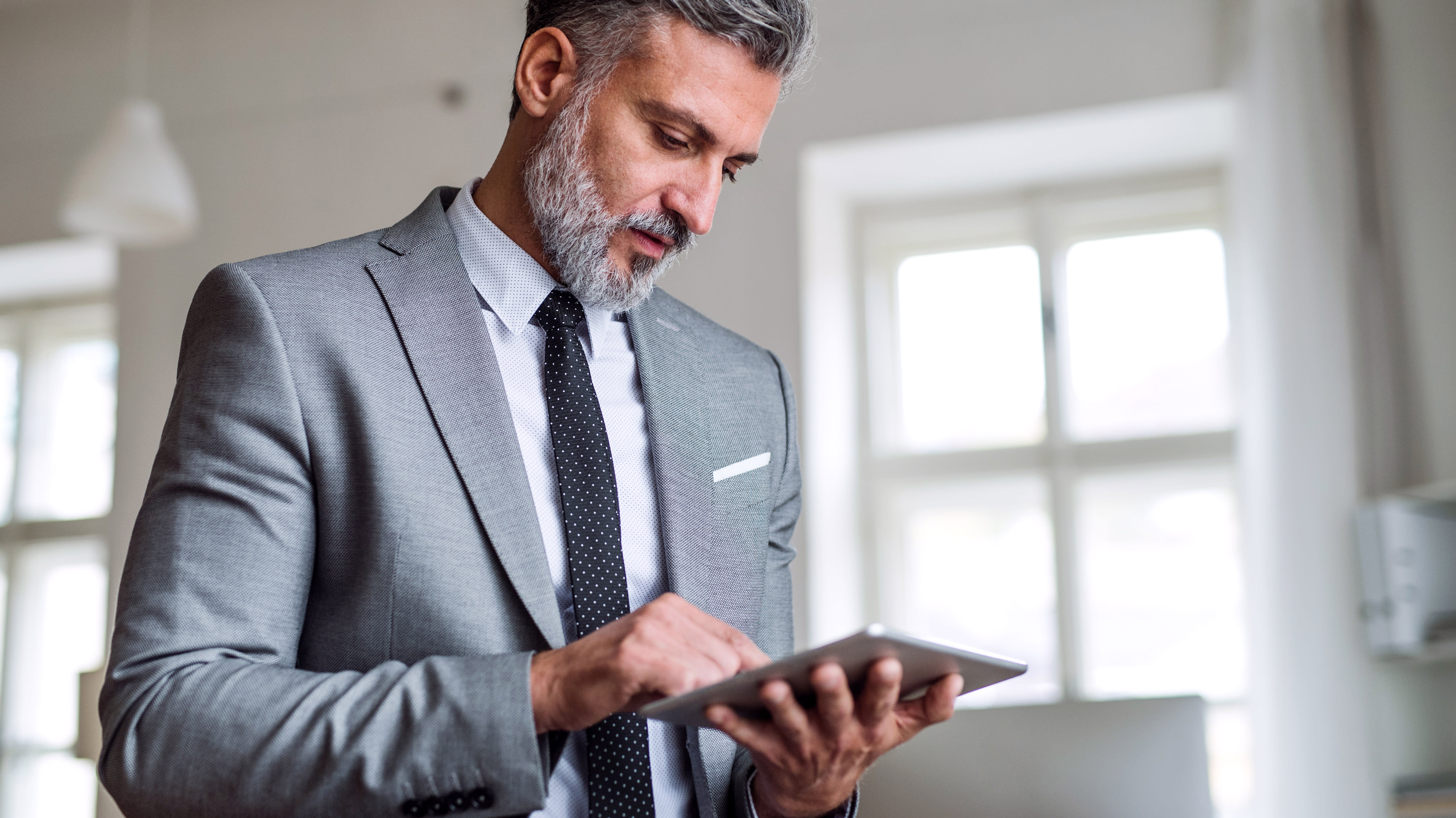 Man, standing on his own, performs a task in OnBase with a tablet.
