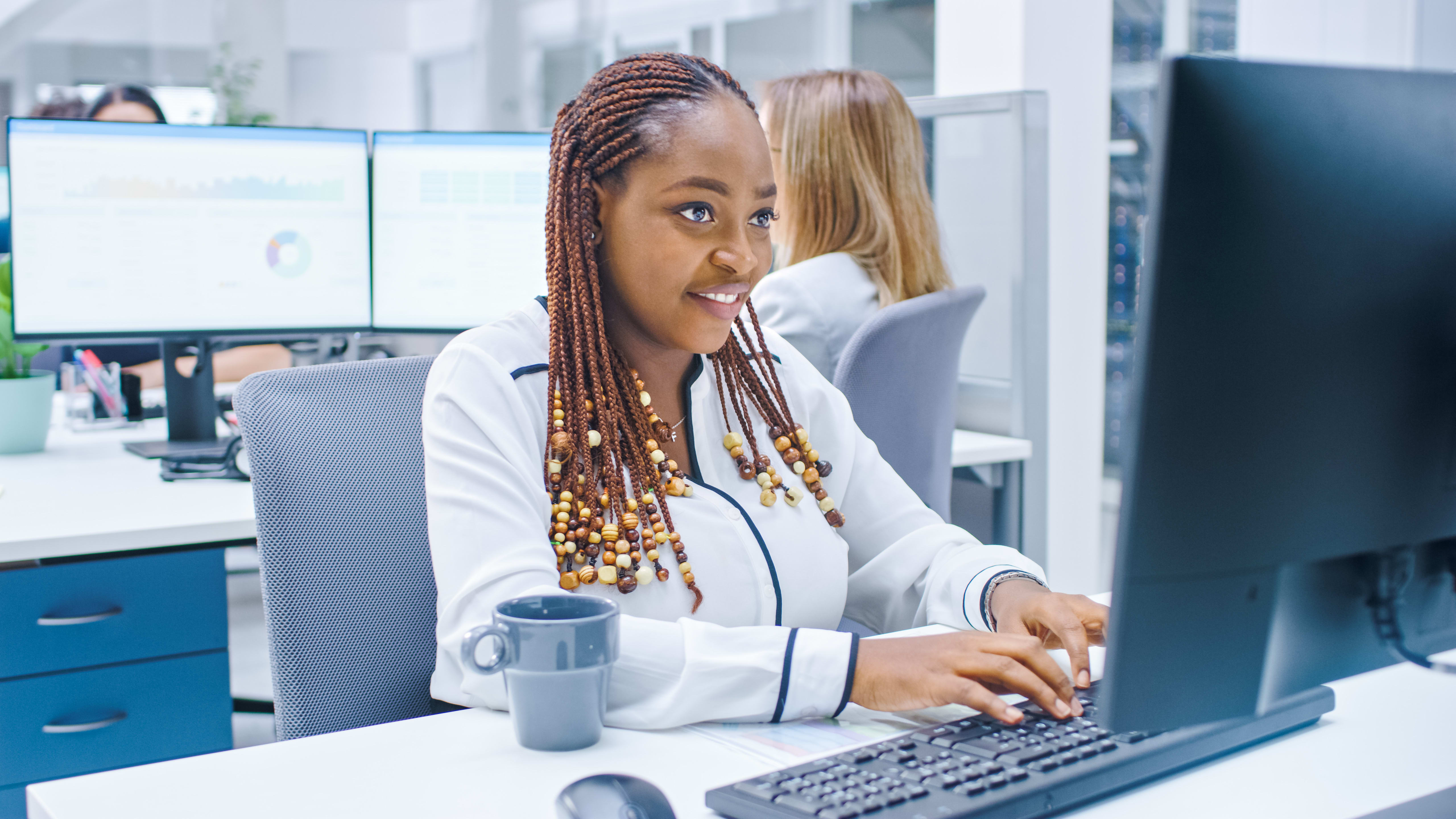 Person smiles and types on a computer keyboard in an office.