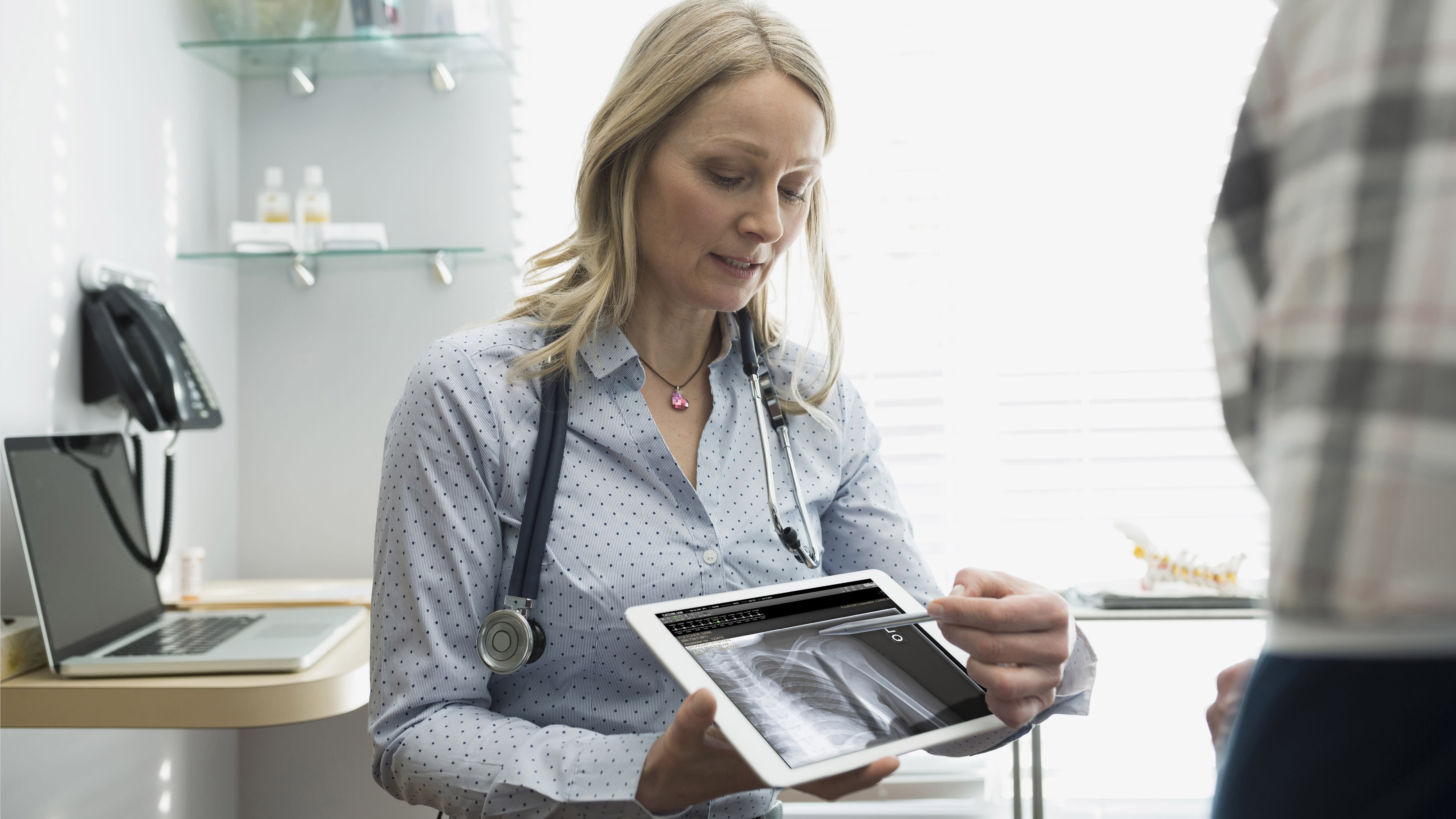 A healthcare professional shows a medical image on a tablet.