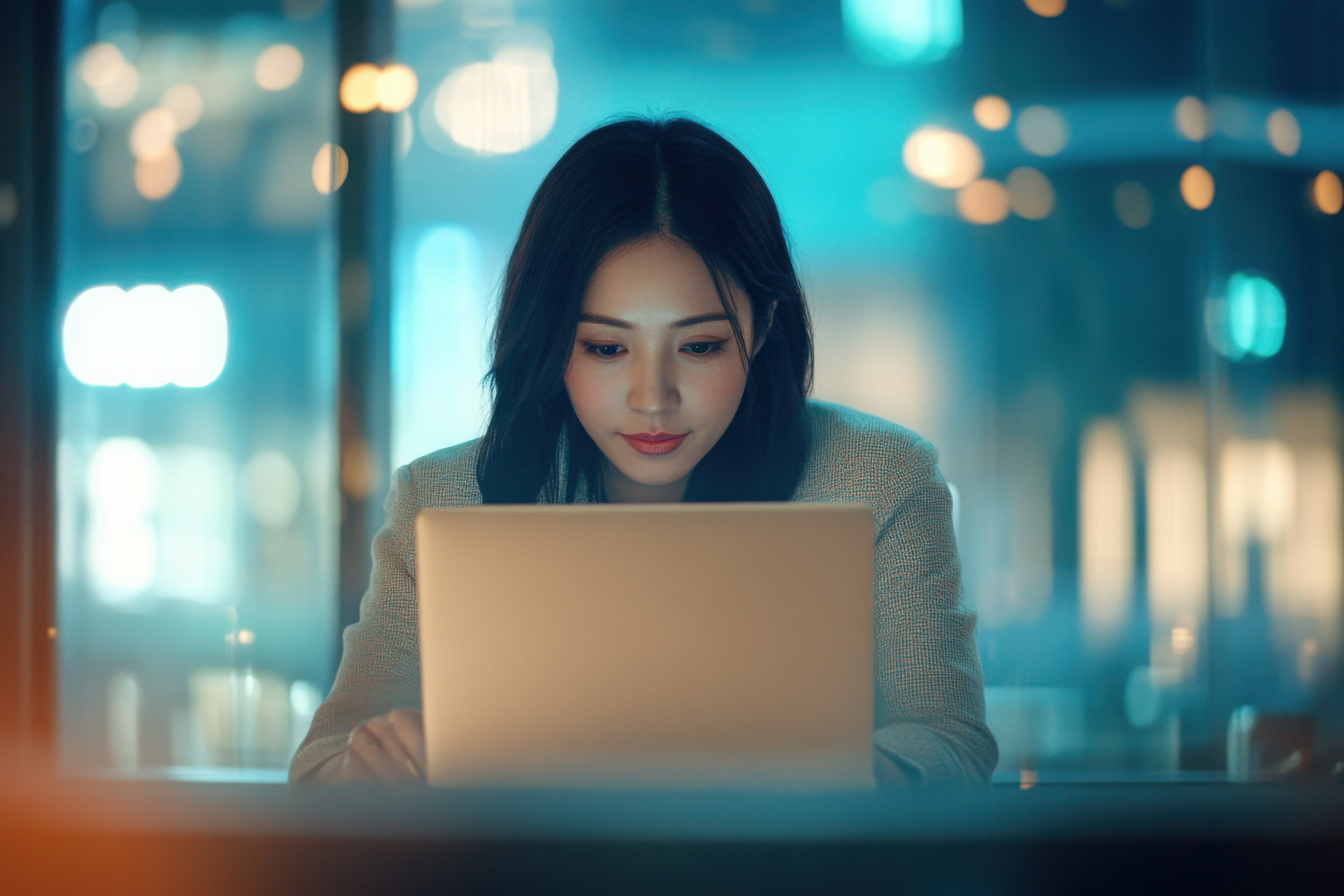 Asian business woman working on a laptop in a professional office.