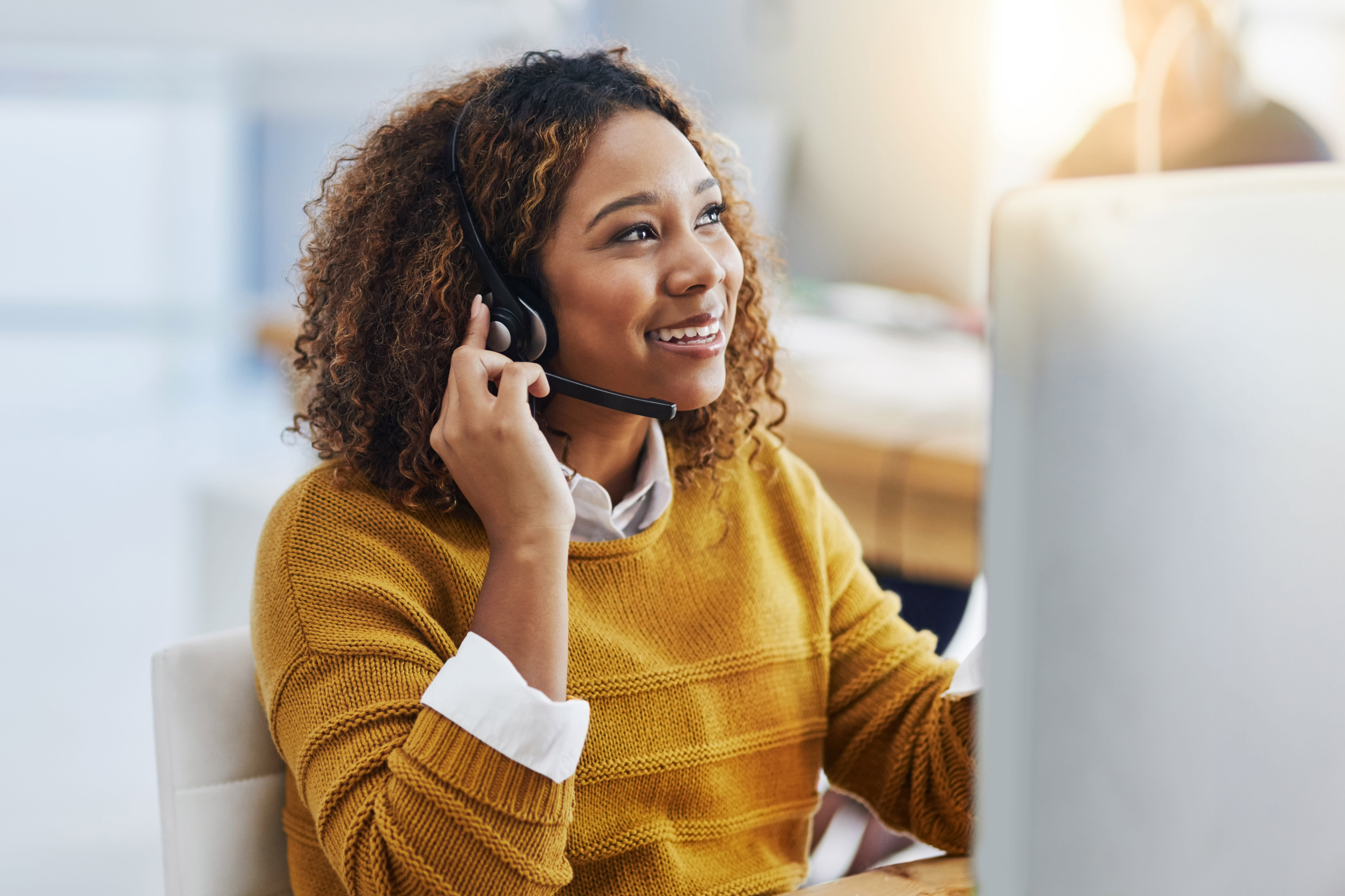 Office worker taking a technical support call in office in front of computer