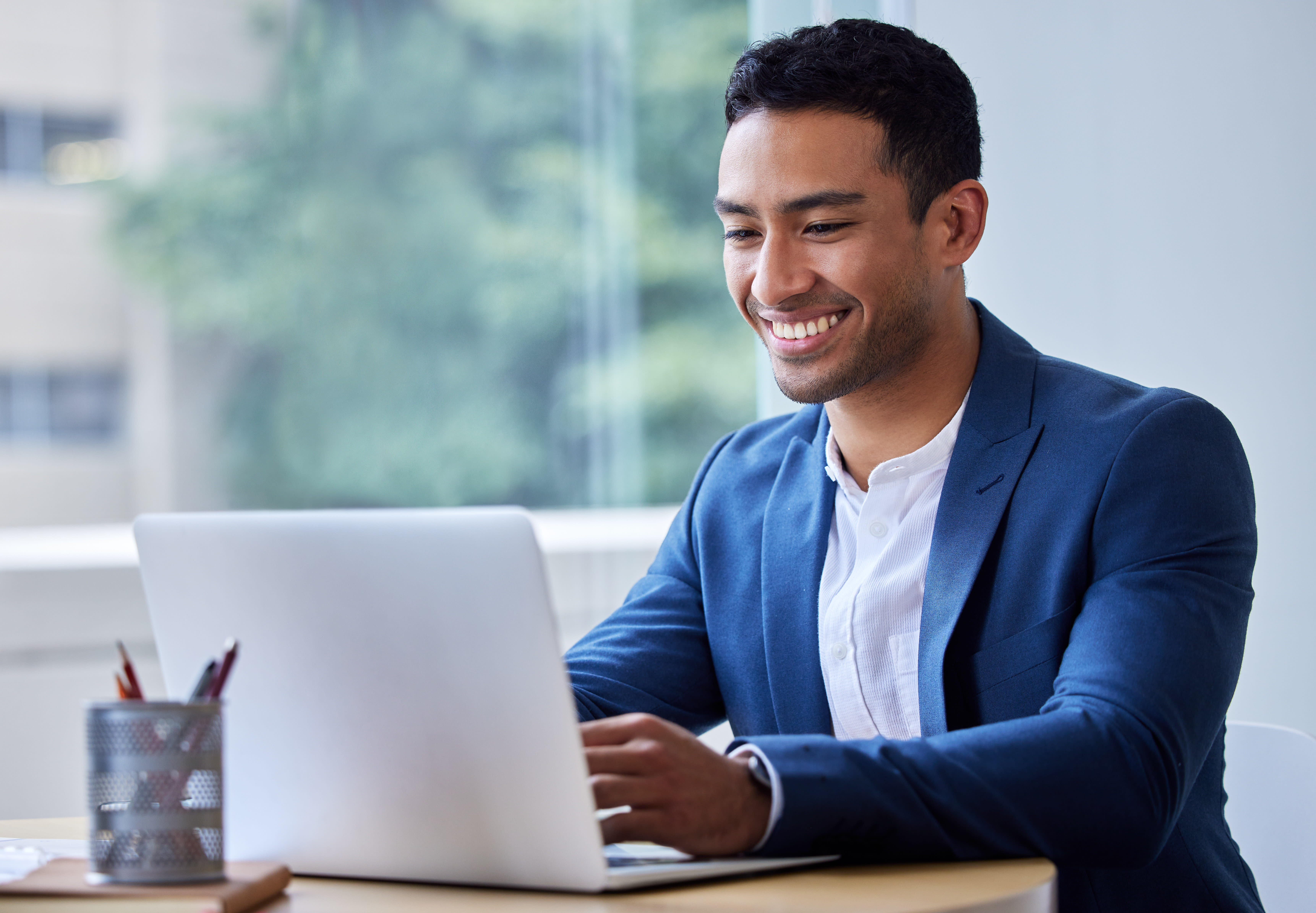 Person sits, smiles and looks at a laptop.