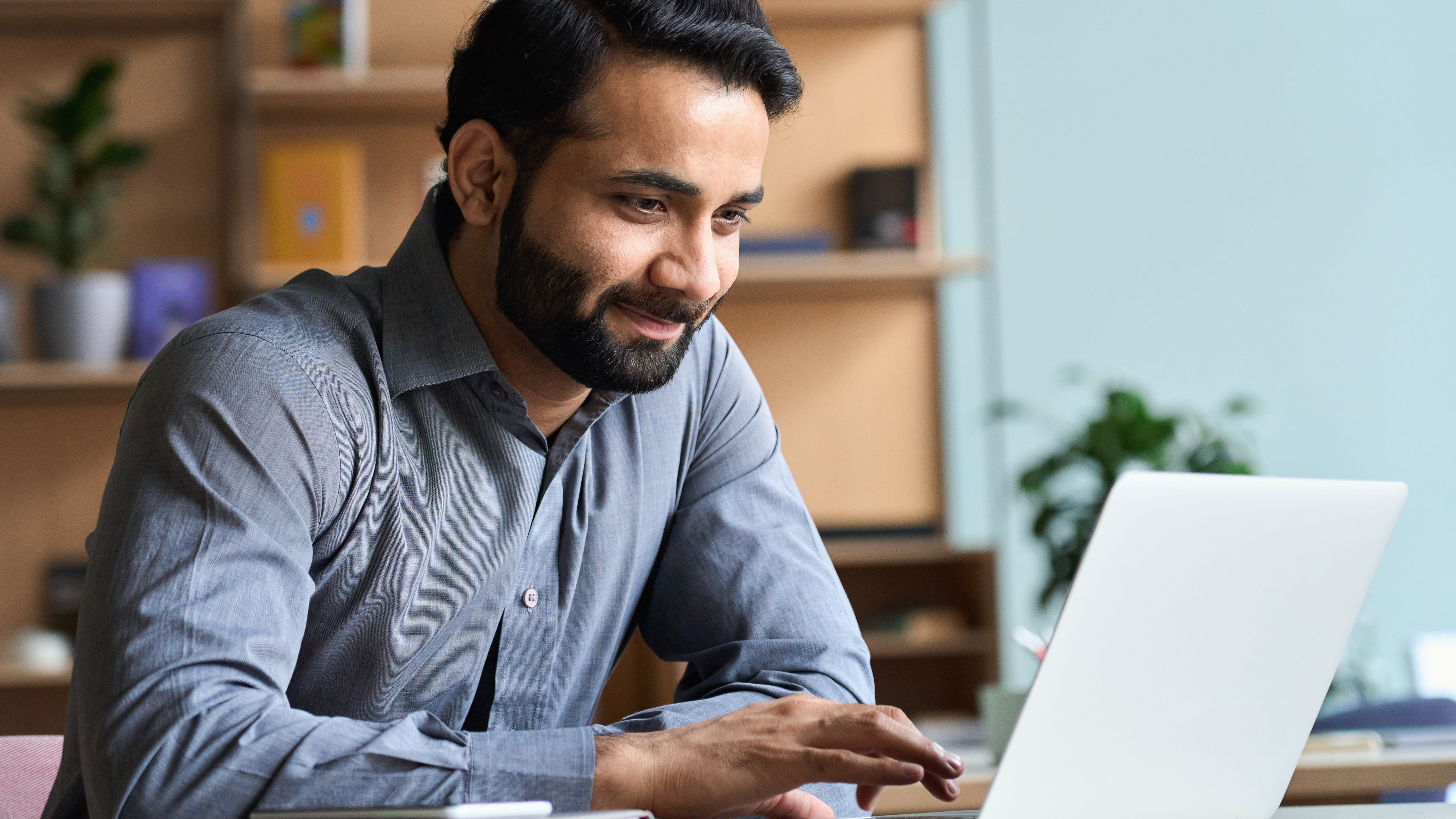 Person sits in office setting at laptop.