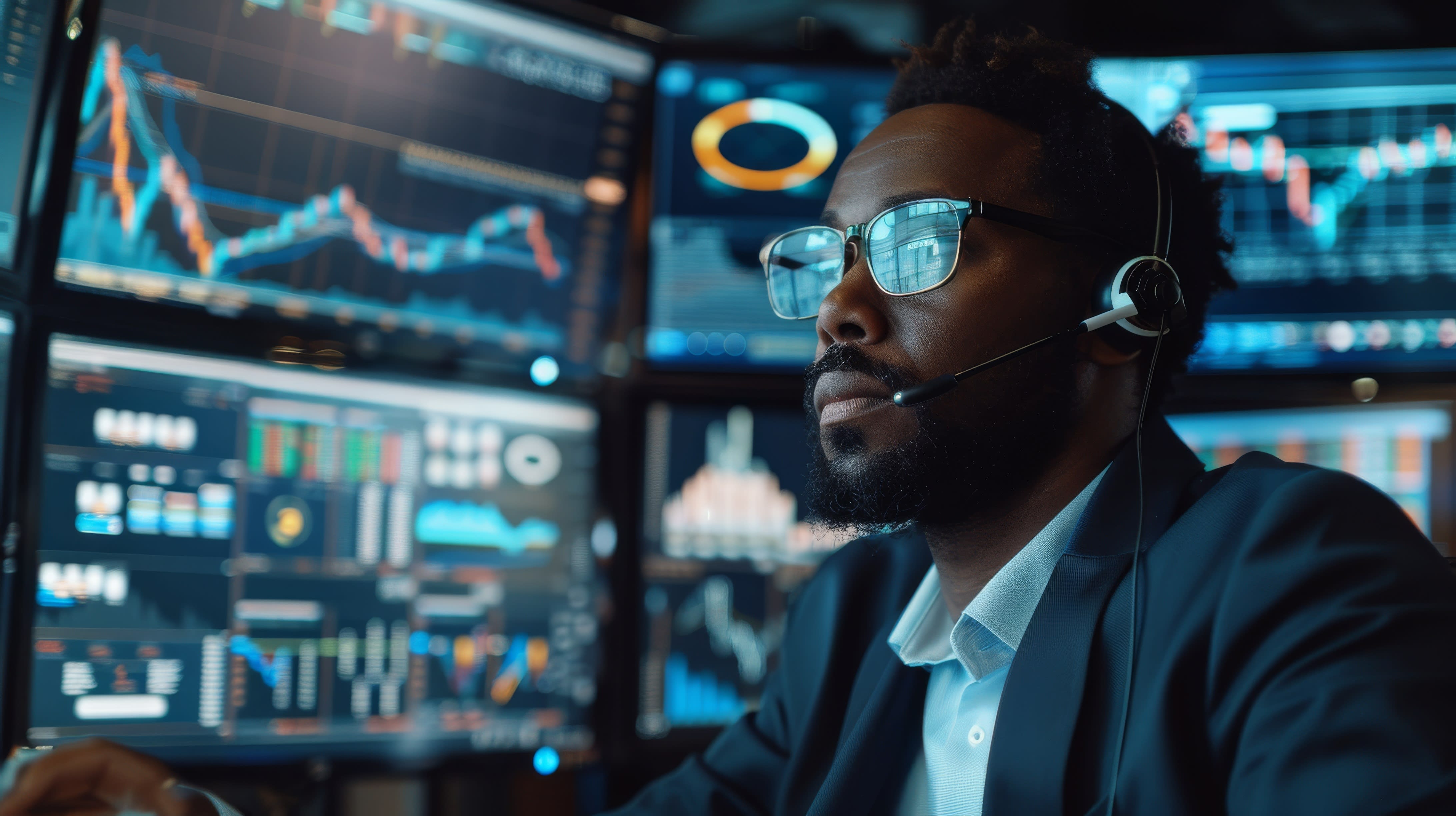 Man with glasses in room filled with screens and data