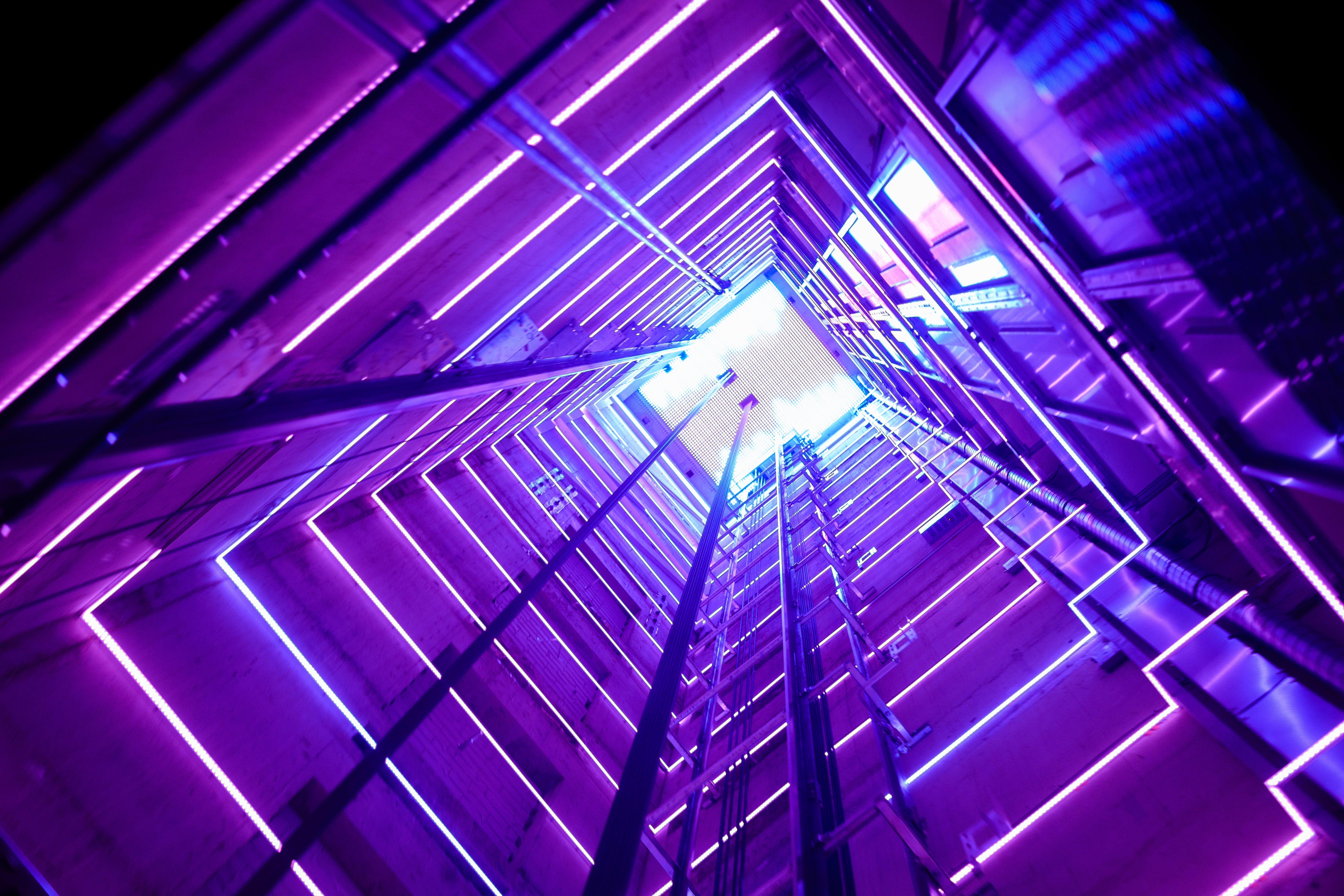  A glass elevator shaft with purple lighting at every level.