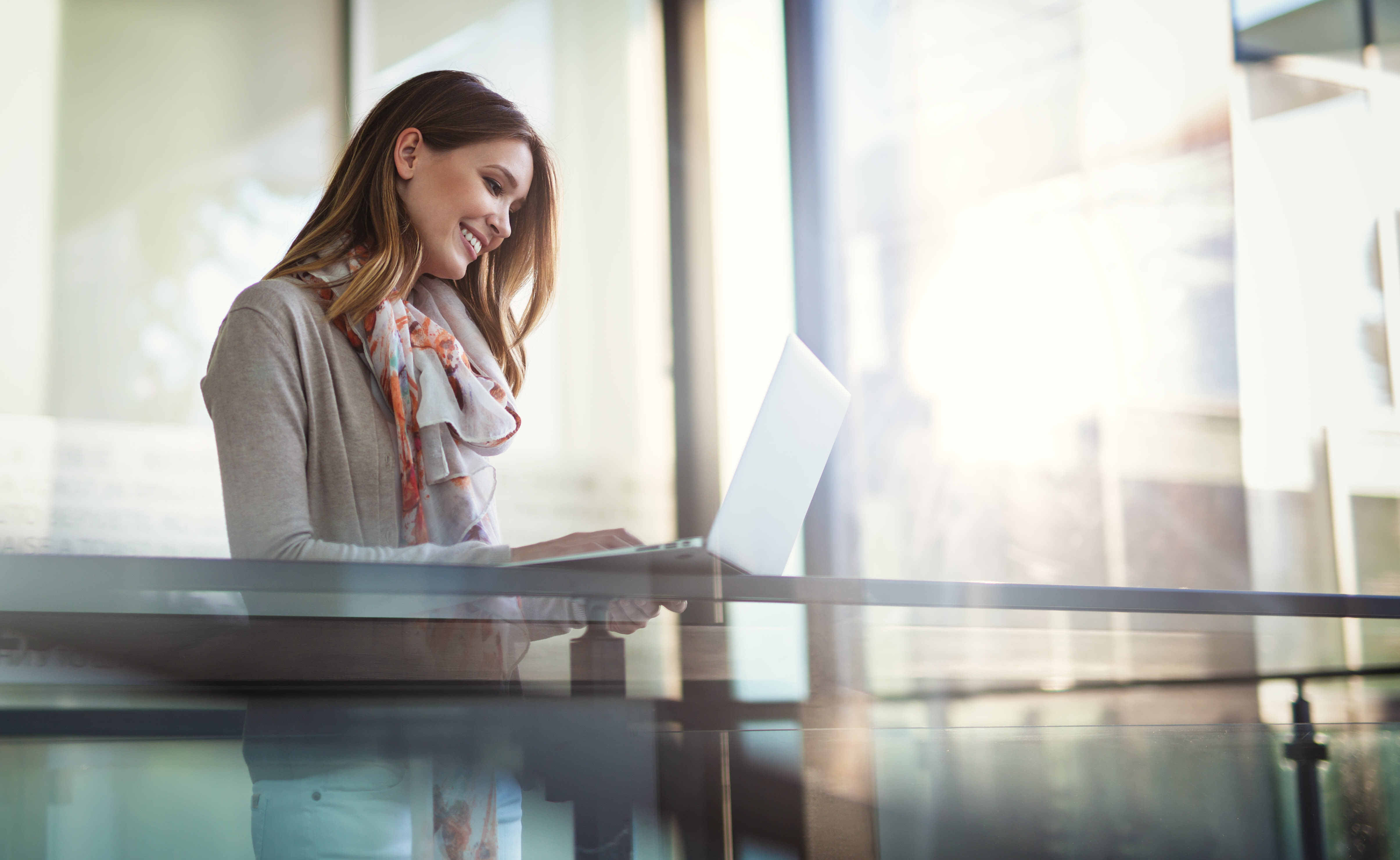 Person uses laptop while sitting in a bright office.