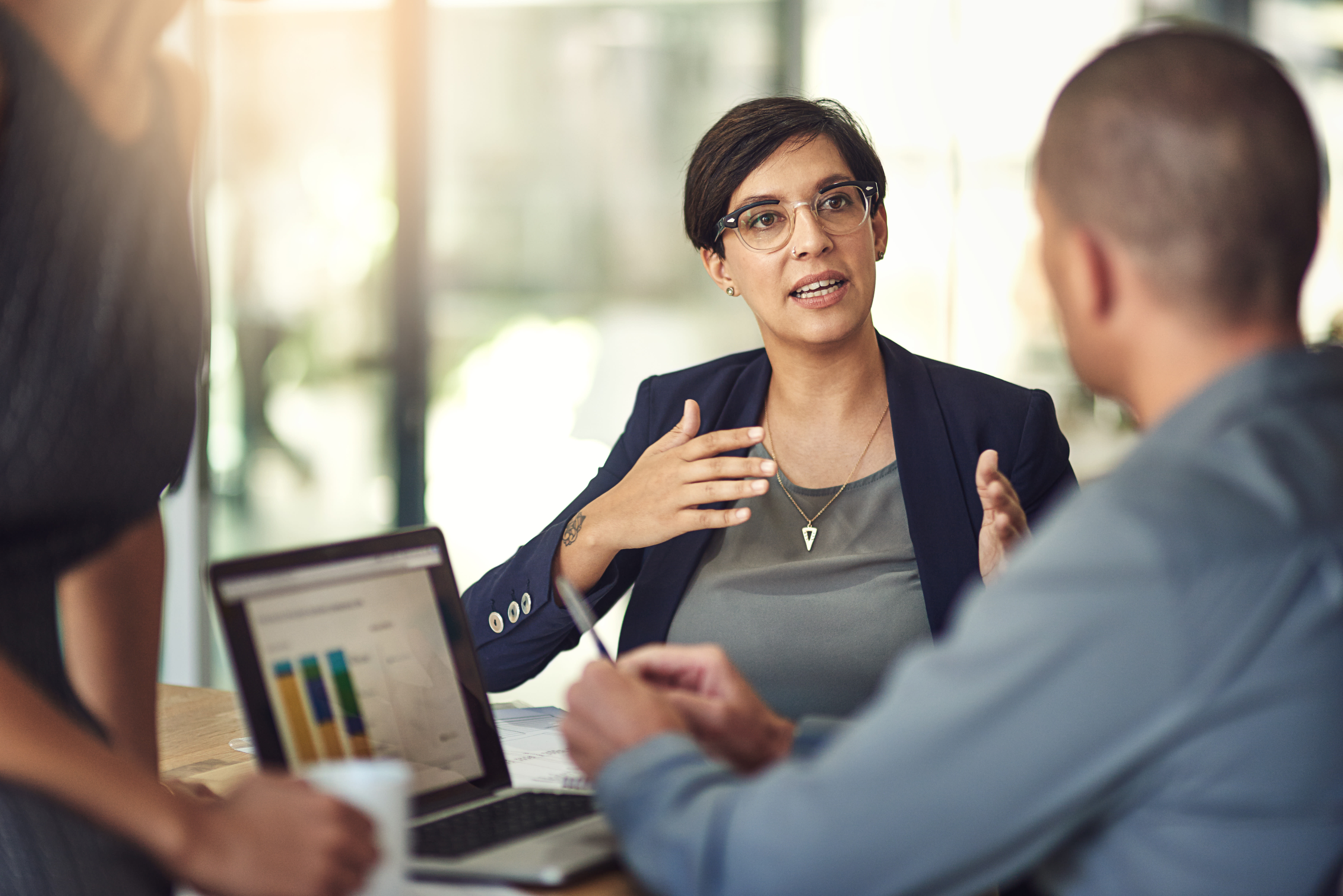 Three co-workers in a modern office setting discuss analyst coverage of Hyland.