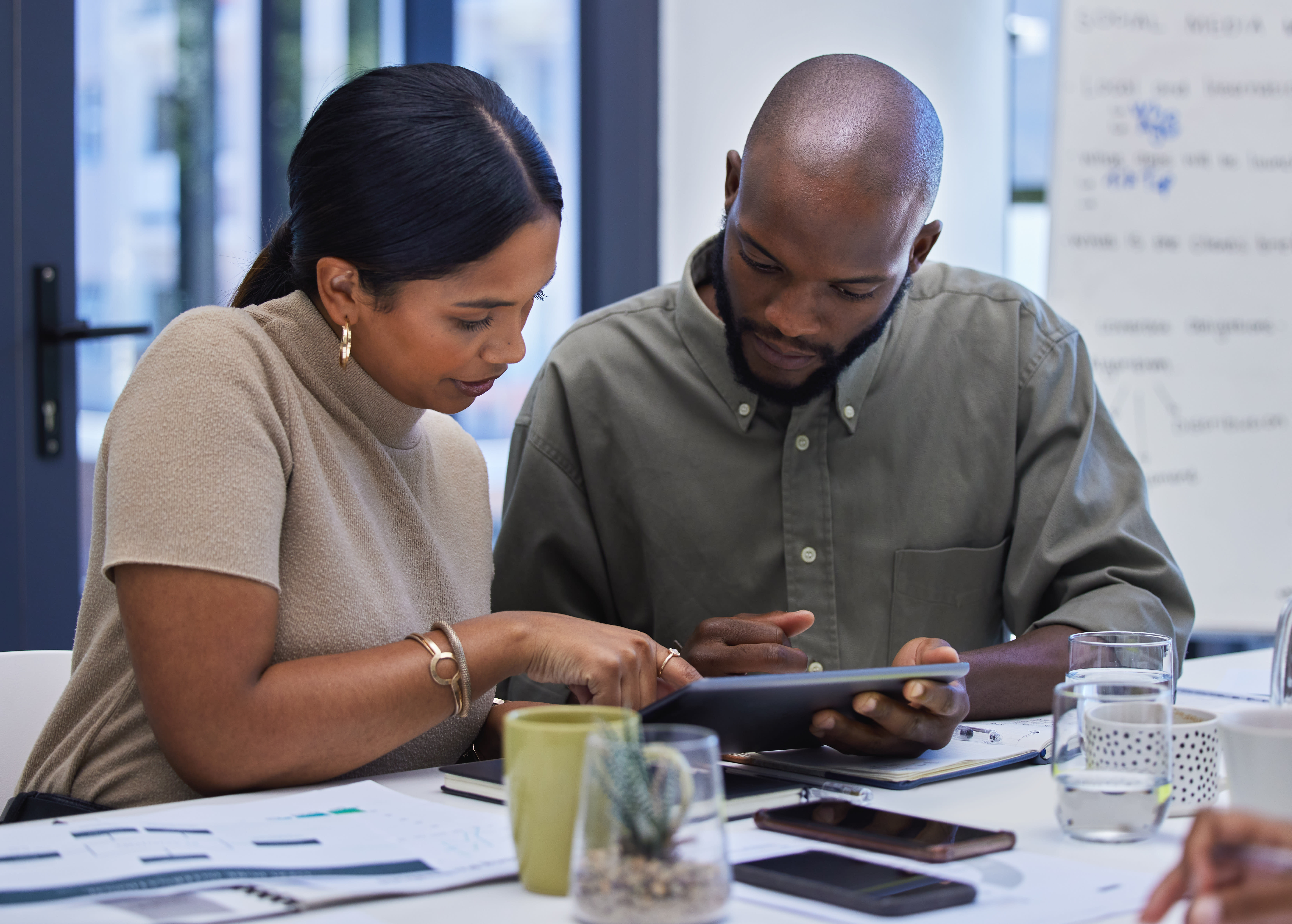 Two office coworkers looking at a tablet