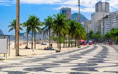 Playa de Copacabana con su paseo costero, palmeras y hoteles frente al mar, ideal para viajeros que eligen Río de Janeiro con Travel Club Agencia de Viajes.