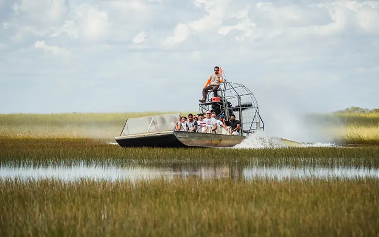 Tour en hidrodeslizador por los Everglades de Miami con turistas explorando los humedales y la fauna local. Ideal para los viajeros aventureros de Agencia de Viajes Travel Club